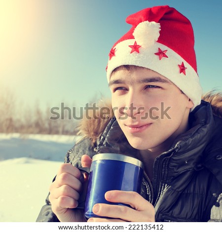 Toned photo of Teenager in Santa\'s Hat with Travel Mug in the Winter