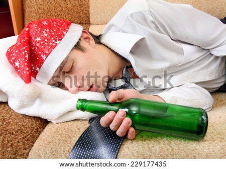 Drunken Teenager sleeping in Santa Hat and Bottle of the Beer on the Sofa