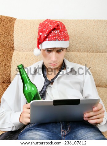 Troubled Teenager in Santa Hat with Tablet Computer and Bottle of the Beer