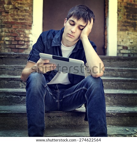 Toned Photo of Sad Teenager with Tablet Computer on the landing steps of the House