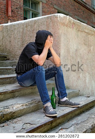 Sad Young Man on the landing steps with a Bottle of the Beer