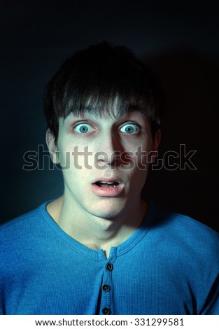Toned Photo of Frightened Young Man in the Dark Room