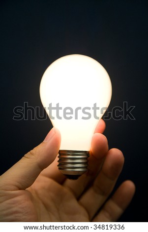 Hand holding a Bright Light Bulb, Concept of Inspiration, Ideas