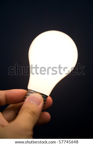 Hand holding a Bright Light Bulb, Concept of Inspiration, Ideas
