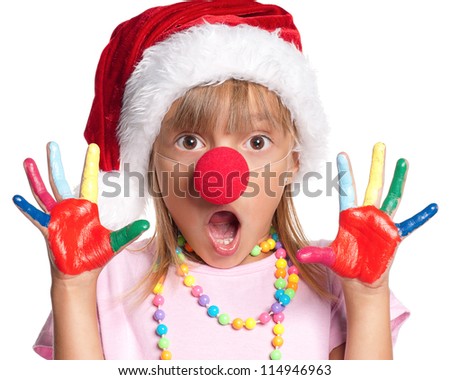 Happy little girl in Santa hat with paints on hands and red clown nose isolated on white background