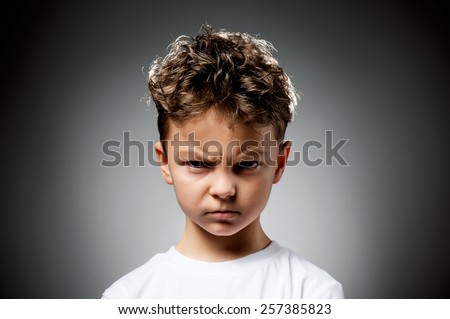 Portrait of boy anger on gray background