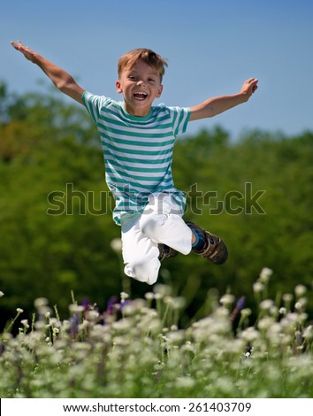 Happy boy jumping for joy on a meadow