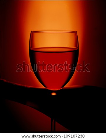 Glass full of wine, and bottle in back round