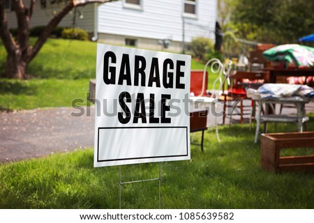 Garage sale sign on the lawn of a suburban home
