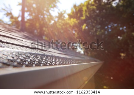 Sun shining on mesh plastic guard in the gutter on a roof