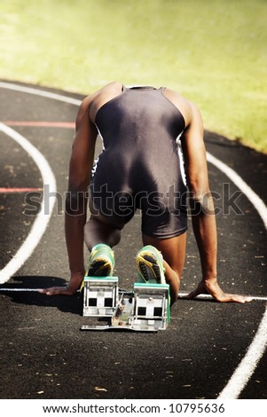 Man in blocks on the starting line of a race (main focus on shoes and blocks)