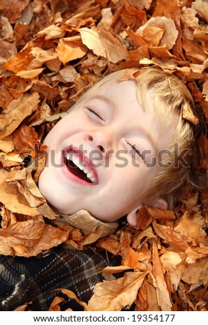 Laughing boy in a pile of leaves
