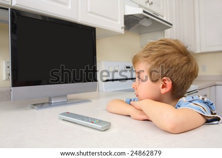 Young boy watching TV in a kitchen