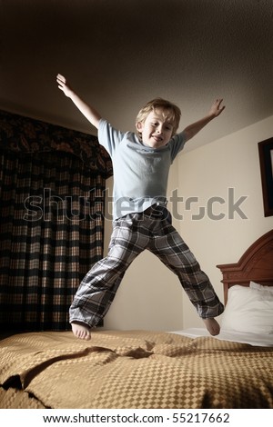 Young boy jumping on the bed