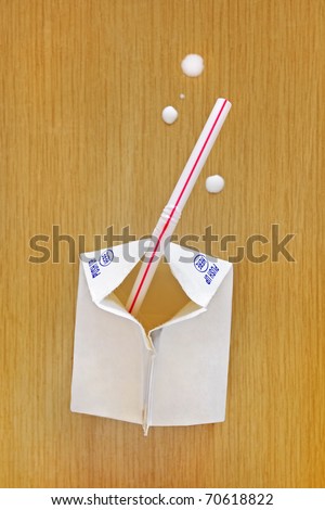 Half pint milk carton with a straw and drops of milk