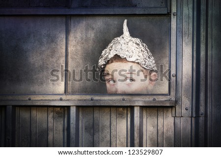 Boy in a tin foil hat peeking out of a window