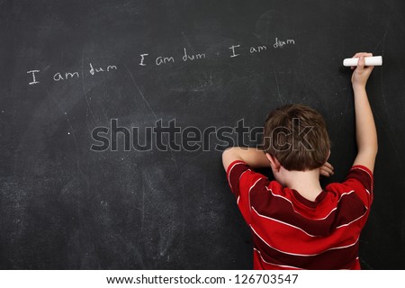 Boy with poor spelling and low self esteem writing on a blackboard