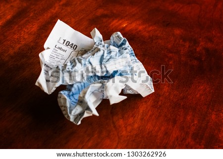 Paper tax form, old school style, crumpled up on a wooden table