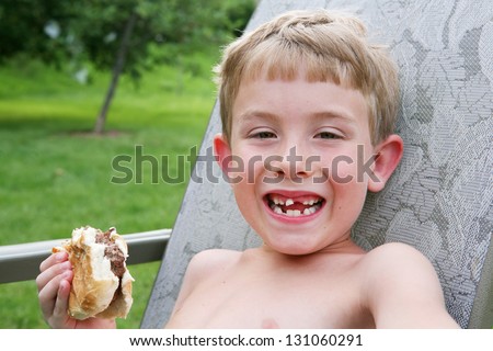 Boy eating outside, with a very loose front tooth
