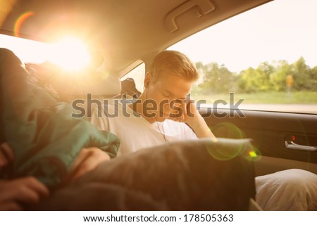 Teenager sleeping in the backseat of a car on a trip