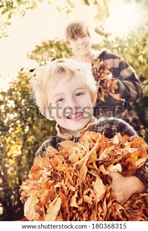 Brothers playing with autumn leaves