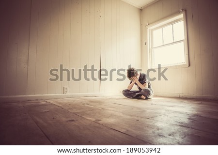 Sad boy alone in a bare room