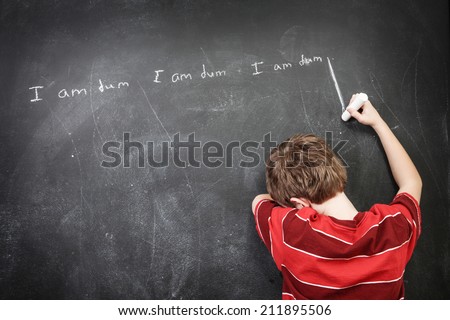 Boy with learning disabilities writing sentences on the blackboard