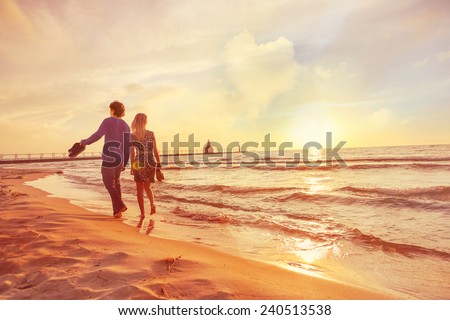 Couple walking on the beach at sunset. Heart shaped cloud in sky. Instagram filter