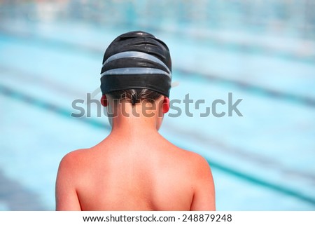Boy with sunburn back in a swim cap by a pool.  Focus on shoulders