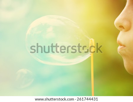 Child blowing bubbles.  Instagram effect.  Focus on lips and edge of bubble wand.