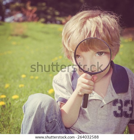 Preschool boy looking through a magnifying glass.