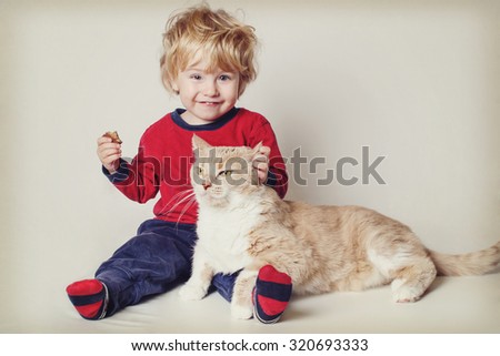 Smiling toddler boy with his pet cat. Vintage toned image. Focus on cat\'s face.