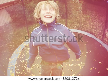 Smiling boy jumping on a trampoline, Instagram filter effect.