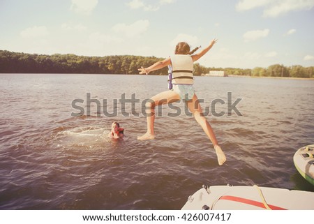 Kids jumping off a boat into the lake. Vintage Instagram effect. Some motion blur
