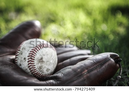 Vintage baseball glove and ball on grass. Very shallow focus on stitching