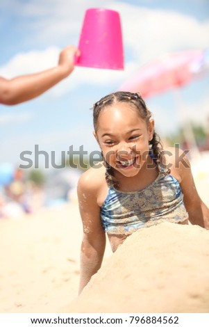 Smiling girl buried in the sand at the beach