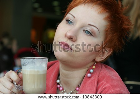 woman dreanking coffee in cafe and thoughtfully looks afar