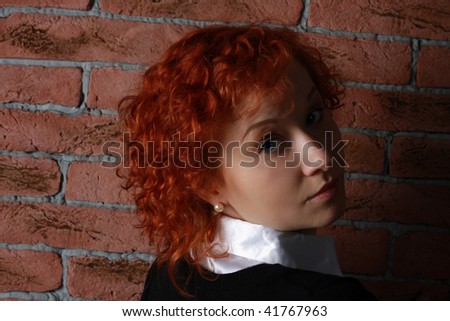 redheaded young woman in studio near brick wall