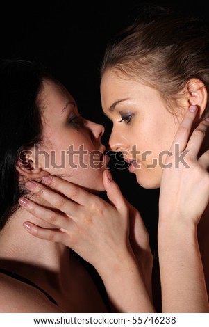 Tender kiss of two young lesbian girl friend on gray background