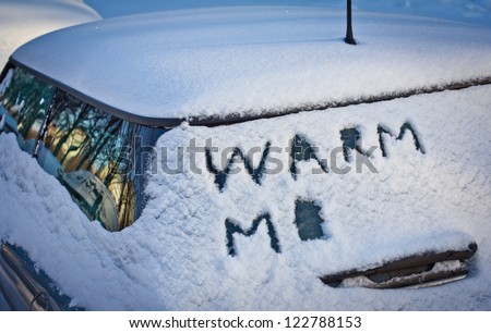 Warm me written in snow on car windscreen below windscreen wiper