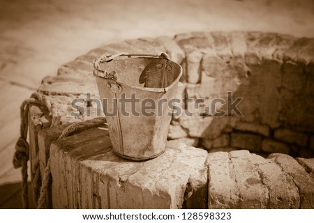 A water well with an old bucket. Vintage style photo.