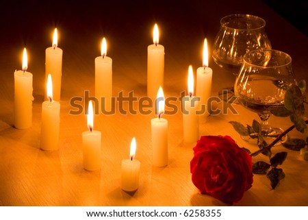 Romantic table with flaming  heart of candles, two glasses of wine and red rose.