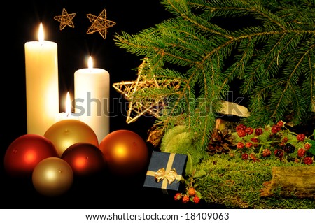 Red, orange and yellow Christmas balls, burning candles, gift box and golden stars in a wood scenery.