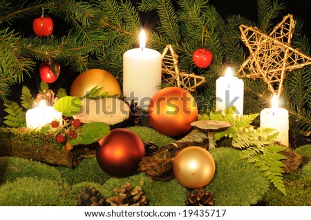 Christmas decoration in the wood setting with Christmas balls, candles, moss, berries and mushrooms.