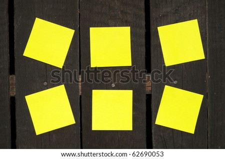 Yellow sticky notes on a wooden wall.