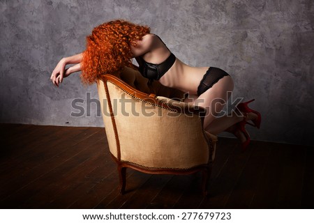 Beautiful young woman kneeling on the chair in lingerie