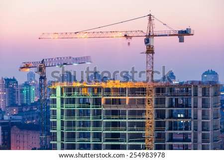 Construction of office building on purple sunset with two tower cranes