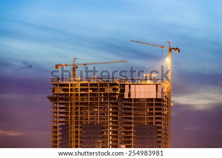 Construction of office building on purple sunset with two tower cranes