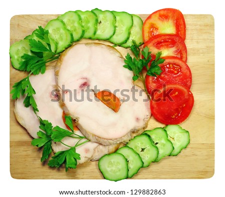 Two pieces of chicken ham with tomatoes and cucumbers on a chopping board isolated on white background
