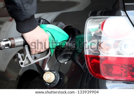 Male Hand Refilling the black Car with Fuel on a Filling Station